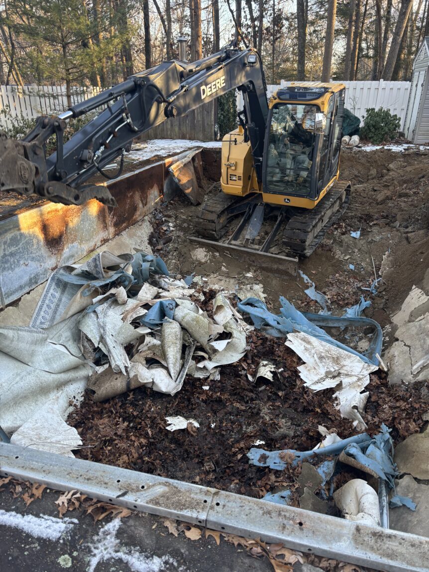 In-ground pool demolition in Milford CT with excavator and removed liner material
