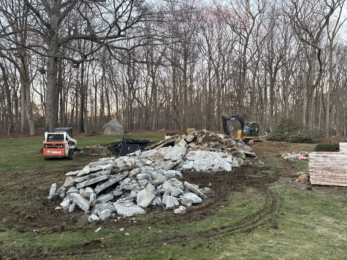 Bobcat and excavator with massive broken concrete pile from inground pool demolition – New Canaan CT